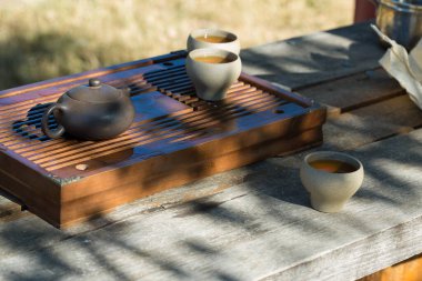 Çin çay seremonisi. Balçıktan yapılmış seramik çaydanlık ve ahşap bir arka planda kaseler.