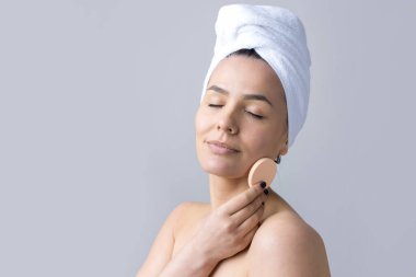 Kafasında beyaz havluyla güzel bir kadın portresi ve pembe bir kalbe bakan bir vücut için sünger. Cilt temizleme eko organik kozmetik rahatlama konsepti.