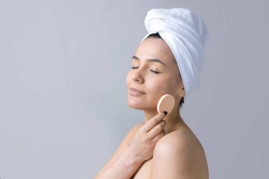 Kafasında beyaz havluyla güzel bir kadın portresi ve pembe bir kalbe bakan bir vücut için sünger. Cilt temizleme eko organik kozmetik rahatlama konsepti.