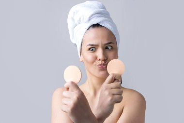 Kafasında beyaz havluyla güzel bir kadın portresi ve pembe bir kalbe bakan bir vücut için sünger. Cilt temizleme eko organik kozmetik rahatlama konsepti.