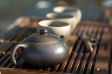 Çin çay seremonisi. Balçıktan yapılmış seramik çaydanlık ve ahşap bir arka planda kaseler.