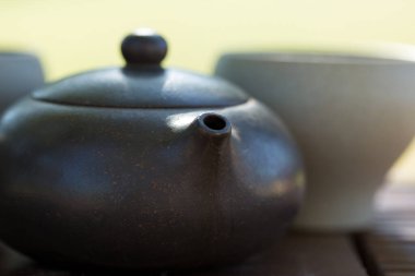 Çin çay seremonisi. Balçıktan yapılmış seramik çaydanlık ve ahşap bir arka planda kaseler.