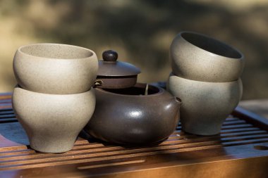 Çin çay seremonisi. Balçıktan yapılmış seramik çaydanlık ve ahşap bir arka planda kaseler.