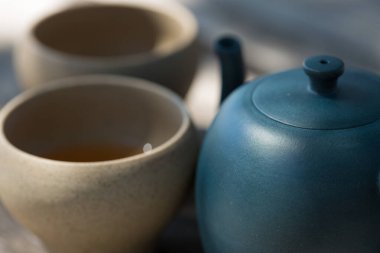 Çin çay seremonisi. Balçıktan yapılmış seramik çaydanlık ve ahşap bir arka planda kaseler.