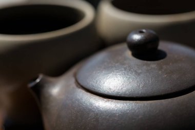 Çin çay seremonisi. Balçıktan yapılmış seramik çaydanlık ve ahşap bir arka planda kaseler.