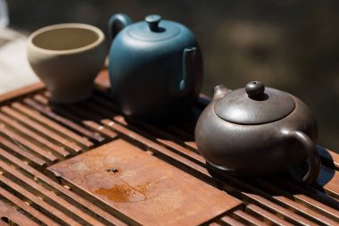 Çin çay seremonisi. Balçıktan yapılmış seramik çaydanlık ve ahşap bir arka planda kaseler.