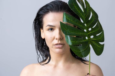 Doğal yeşil palmiye yaprağı portresi olan bir kadın. Moda, güzellik, makyaj, kozmetik.
