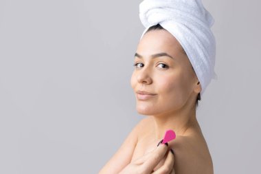 Kafasında beyaz havluyla güzel bir kadın portresi ve pembe bir kalbe bakan bir vücut için sünger. Cilt temizleme eko organik kozmetik rahatlama konsepti.