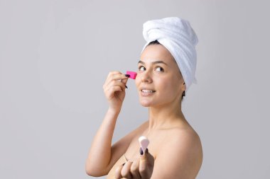 Kafasında beyaz havluyla güzel bir kadın portresi ve pembe bir kalbe bakan bir vücut için sünger. Cilt temizleme eko organik kozmetik rahatlama konsepti.