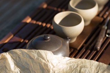 Çin çay seremonisi. Balçıktan yapılmış seramik çaydanlık ve ahşap bir arka planda kaseler.