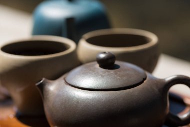Çin çay seremonisi. Balçıktan yapılmış seramik çaydanlık ve ahşap bir arka planda kaseler.