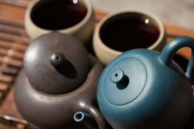 Çin çay seremonisi. Balçıktan yapılmış seramik çaydanlık ve ahşap bir arka planda kaseler.