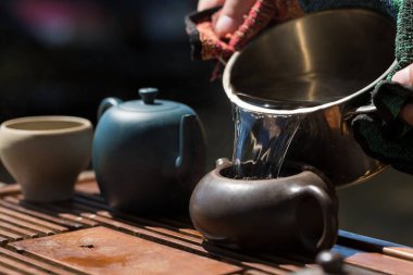 Çin çay seremonisi. Balçıktan yapılmış seramik çaydanlık ve ahşap bir arka planda kaseler.