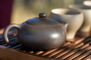 Çin çay seremonisi. Balçıktan yapılmış seramik çaydanlık ve ahşap bir arka planda kaseler.