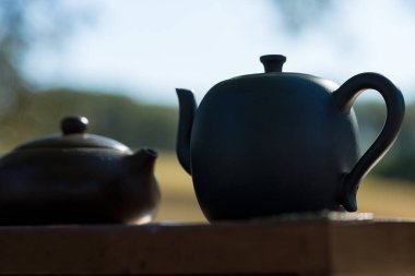 Çin çay seremonisi. Balçıktan yapılmış seramik çaydanlık ve ahşap bir arka planda kaseler.