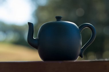 Çin çay seremonisi. Balçıktan yapılmış seramik çaydanlık ve ahşap bir arka planda kaseler.