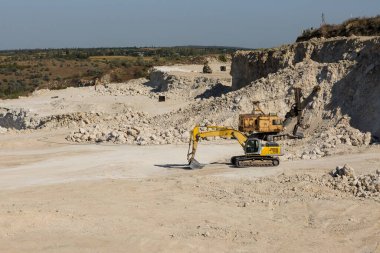 Büyük sarı çizgili bir kazıcı taş ocağında kaya çıkarıyor..