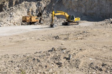 Büyük sarı çizgili bir kazıcı taş ocağında kaya çıkarıyor..