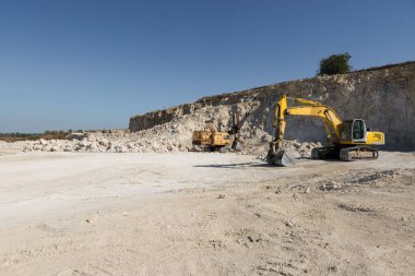 Büyük sarı çizgili bir kazıcı taş ocağında kaya çıkarıyor..
