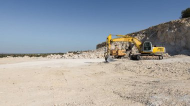 Büyük sarı çizgili bir kazıcı taş ocağında kaya çıkarıyor..