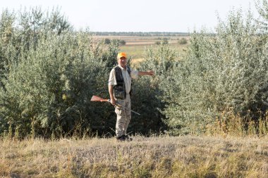 Tüfekli ördek avcısı çayırda yürüyor..