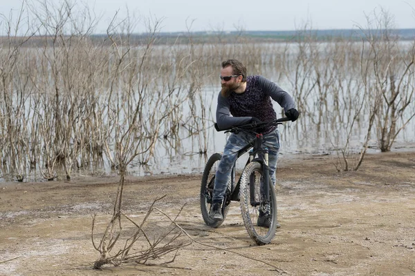 現代のマウンテンバイクで残酷な髭の男をスポーツ 湖に捨てられた塩の中のサイクリスト — ストック写真