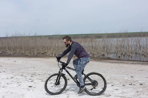 現代のマウンテンバイクで残酷な髭の男をスポーツ 湖に捨てられた塩の中のサイクリスト — ストック写真