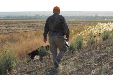 Tüfekli ördek avcısı çayırda yürüyor..