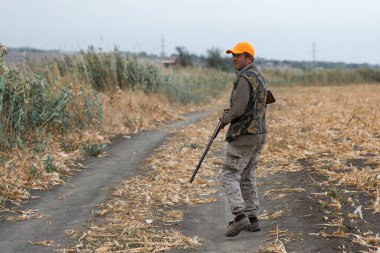Tüfekli ördek avcısı çayırda yürüyor..