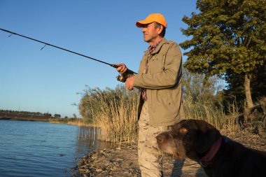 Nehir kenarında duran ve balık tutmaya çalışan bir balıkçı. Spor, eğlence, yaşam tarzı..