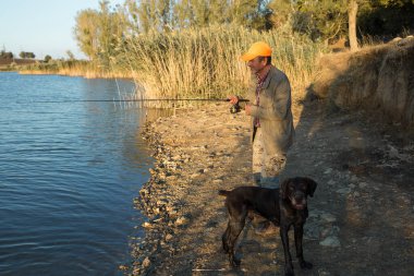 Nehir kenarında duran ve balık tutmaya çalışan bir balıkçı. Spor, eğlence, yaşam tarzı..