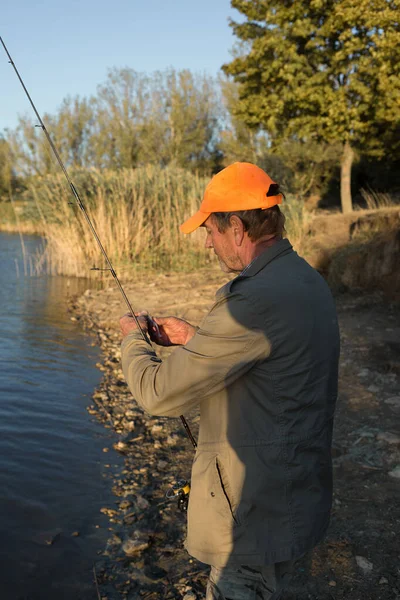 Nehir kenarında duran ve balık tutmaya çalışan bir balıkçı. Spor, eğlence, yaşam tarzı..