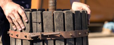 Kırmızılı şarap presi ve sarmal vida. Şarap üreticisinin elleri kapalı..