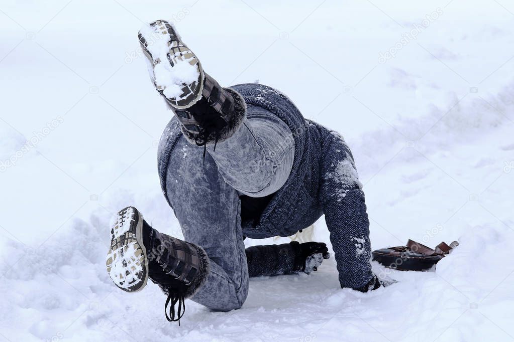 Dangerously slippery roads and sidewalks in winter. A woman slips on a snowy road 