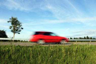 A red car drives very fast over a road clipart