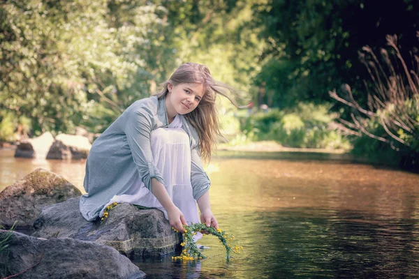 彼女の手の花輪を持つ湖のブロンドの女の子 — ストック写真