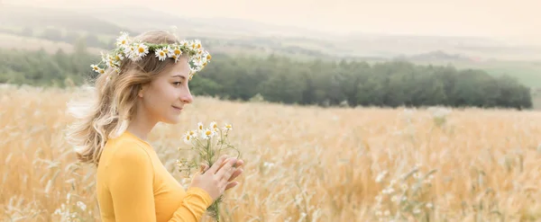 麦畑にカモミールの花束を持つ若い女性 パノラマ画像 — ストック写真