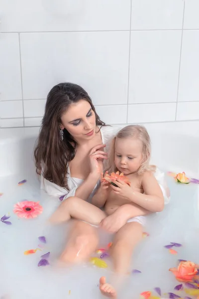 Mutter und Tochter nehmen ein Bad mit Milch und Rosenblüten — Stockfoto