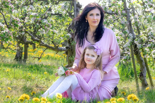 Мати і дочка ходять у квітучому яблучному саду — стокове фото