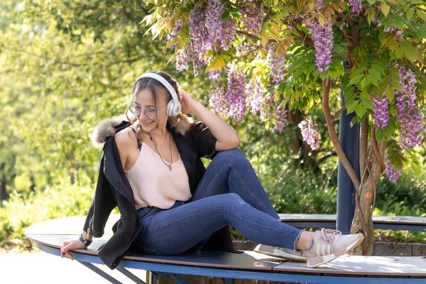 Молода жінка слухає музику в саду з квітучим бажанням — стокове фото
