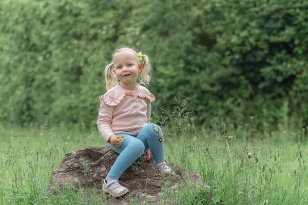 Klein meisje zittend op de steen en lacht — Stockfoto