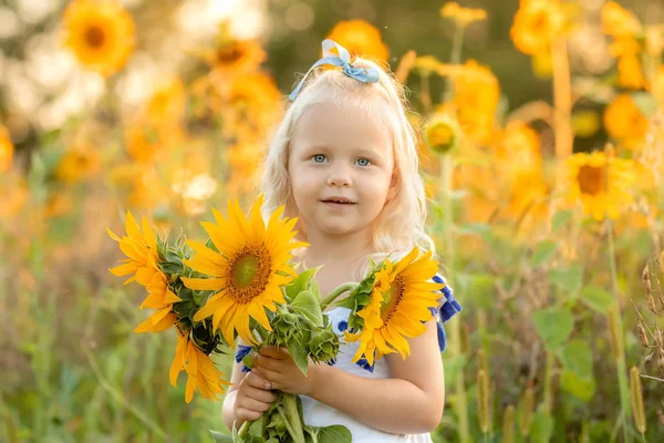 Portrait d'une petite fille avec un bouquet de tournesols — Photo