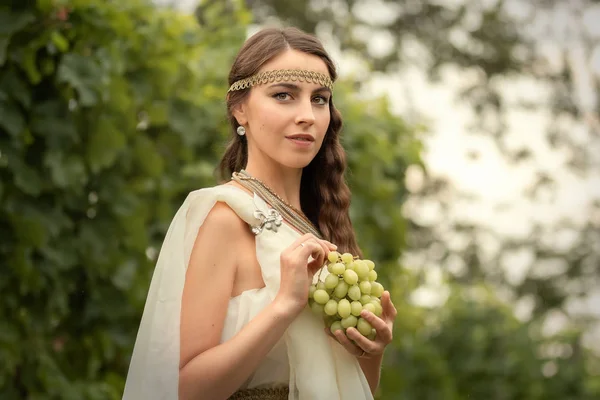 Young woman in tunic harvesting grapes — Stock Photo, Image