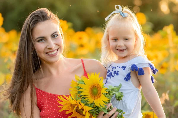 Мати і дочка сміються в полі з соняшниками — стокове фото