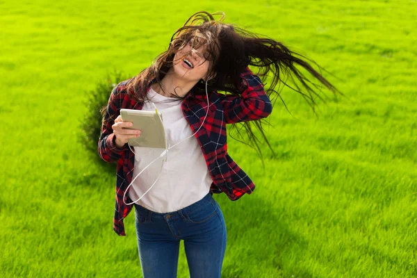 young brunette woman listen top chart song. Jump and dance on the grass