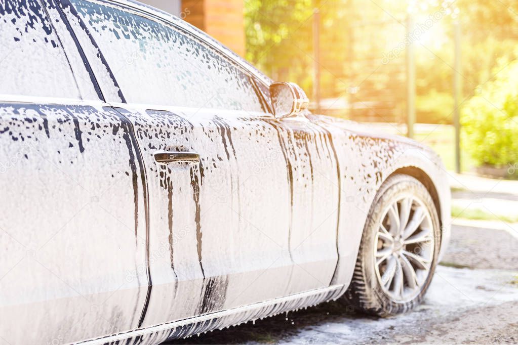 Manual car wash. Washing luxury vehicle with white foamy detergent. Automobile  cleaning self service