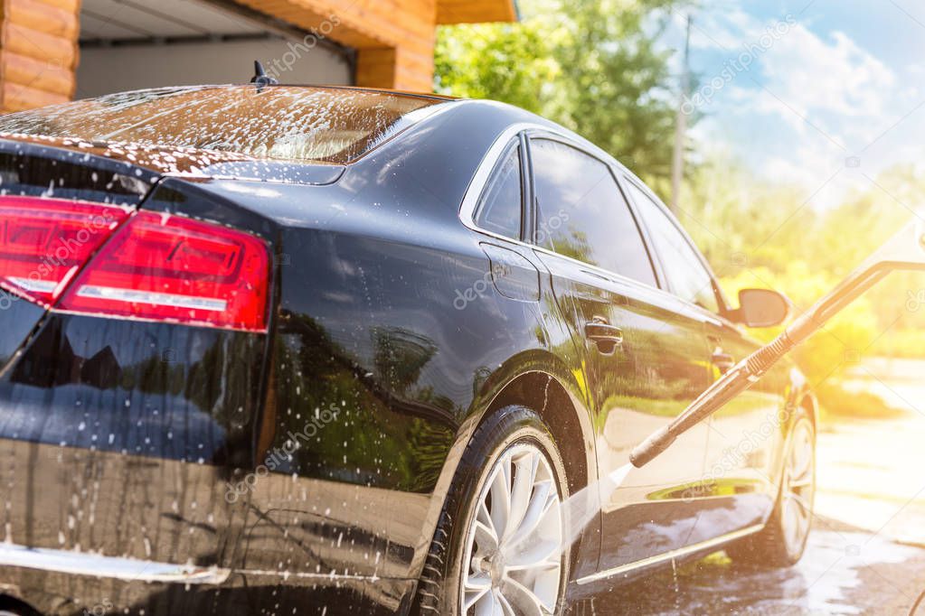 Manual car wash. Washing luxury vehicle with high pressure water