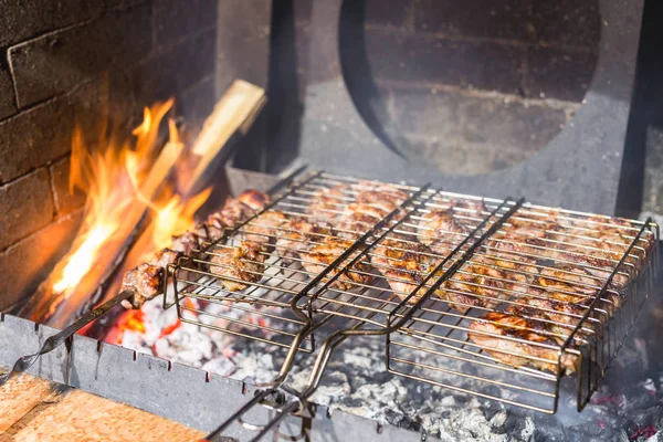 Bistecche di carne alla griglia e spiedini a braciere di pietra con fiamme di fuoco. Barbecue concetto di festa all'aperto — Foto Stock