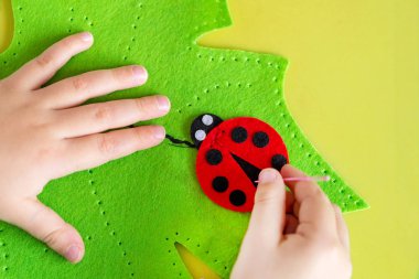 Yaprak yeşil ve kırmızı ladybag keçe yumuşak oyuncak yapma çocuk. Çocuk DIY etkinlik. Yakın çekim. Çocuklar el sanatları kavramı.