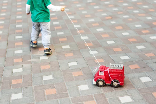 Ребенок Играет Улице Ребенок Несет Веревку Красным Пожарным Грузовиком Уличные — стоковое фото